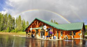 Paddle Ridge gift shop at Glacier Outdoor Center in Glacier National Park under a vivid rainbow arc.