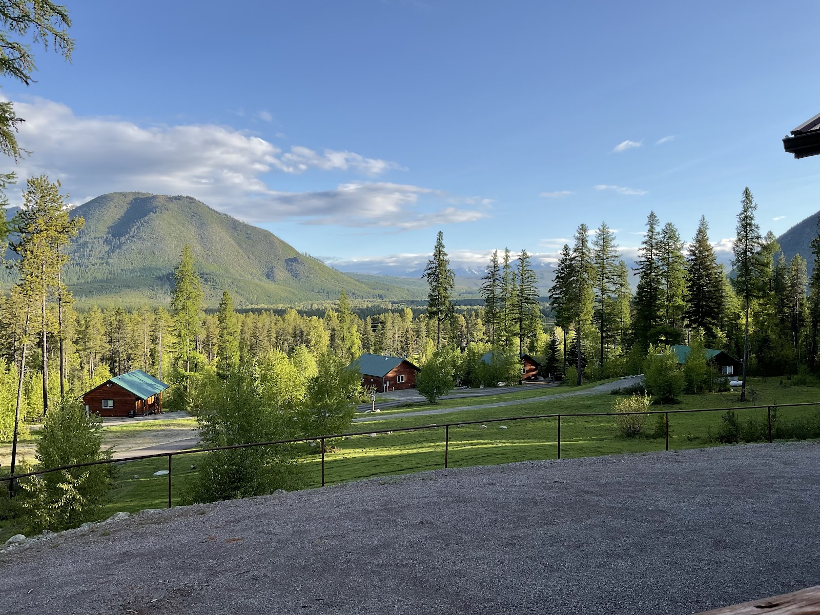 Paddle Ridge scene in Glacier National Park features red cabins tucked among pines with a mountainous backdrop.