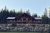 Rustic log lodge gift shop building at Glacier National Park with a stone terrace and evergreen forest backdrop.