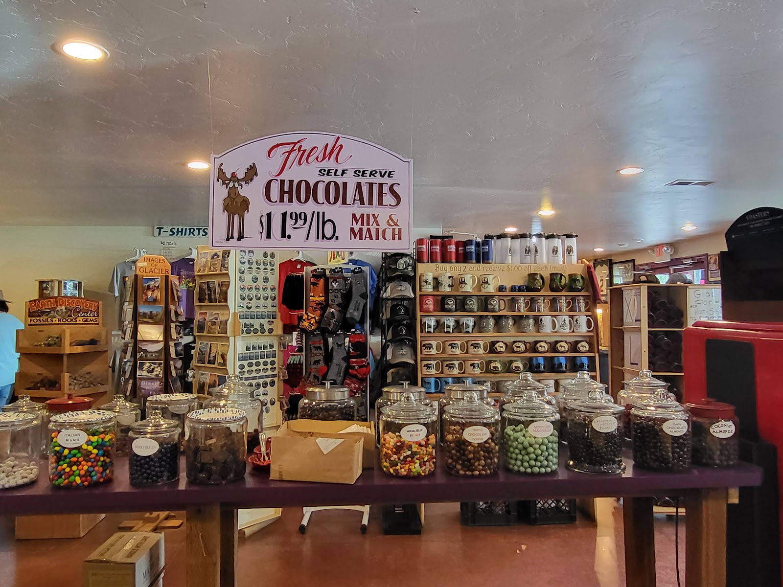 Interior of a Glacier National Park gift shop with colorful candy jars lined up on a long table and souvenirs on the shelves.