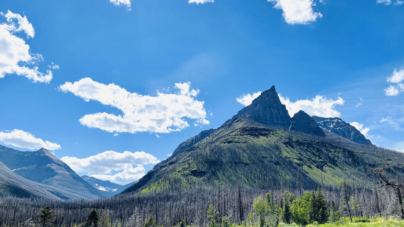 Red Rock Canyon trail winds through rugged terrain with granite peaks in Glacier National Park.