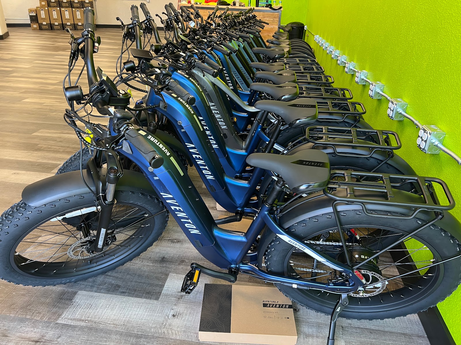 Row of blue Aventon e-bikes lined up inside a Glacier National Park gift shop, ready for sale or rental.