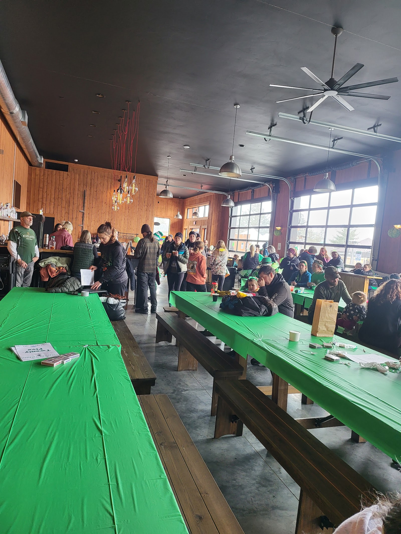 Interior of a Glacier National Park restaurant with long green-table dining, wood-paneled walls, and a crowd of guests.
