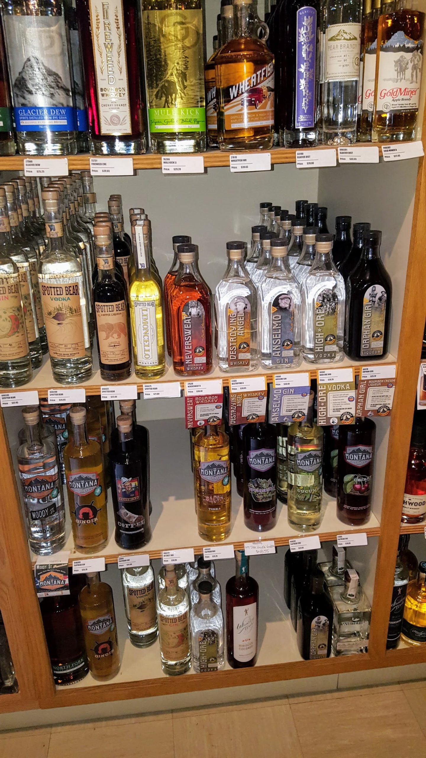 Liquor bottles line a shelf inside Glacier National Park store in Montana, with a variety of brands and labels visible.