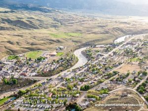 Yellowstone National Park aerial view of a winding river running through a town, with bridges, roads, and rows of RVs and campsites.