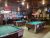 Interior of a rustic Glacier National Park saloon with pool tables, hanging lights, and vintage decor.