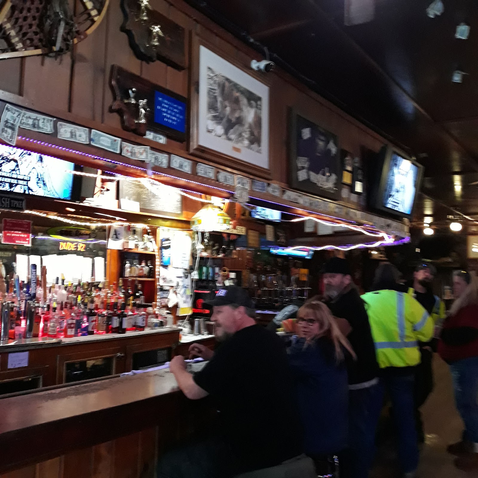 Interior of a rustic glacier national park saloon bar with patrons and bottles on the counter.