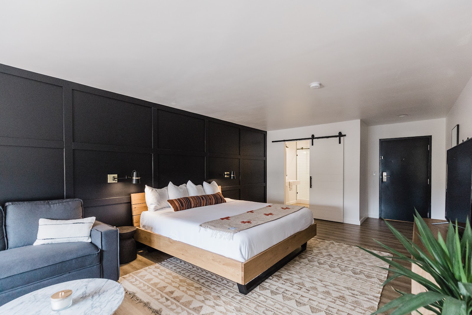 Guest bedroom at a Glacier National Park lodging: dark paneled wall behind a wooden-framed king bed with plush pillows.
