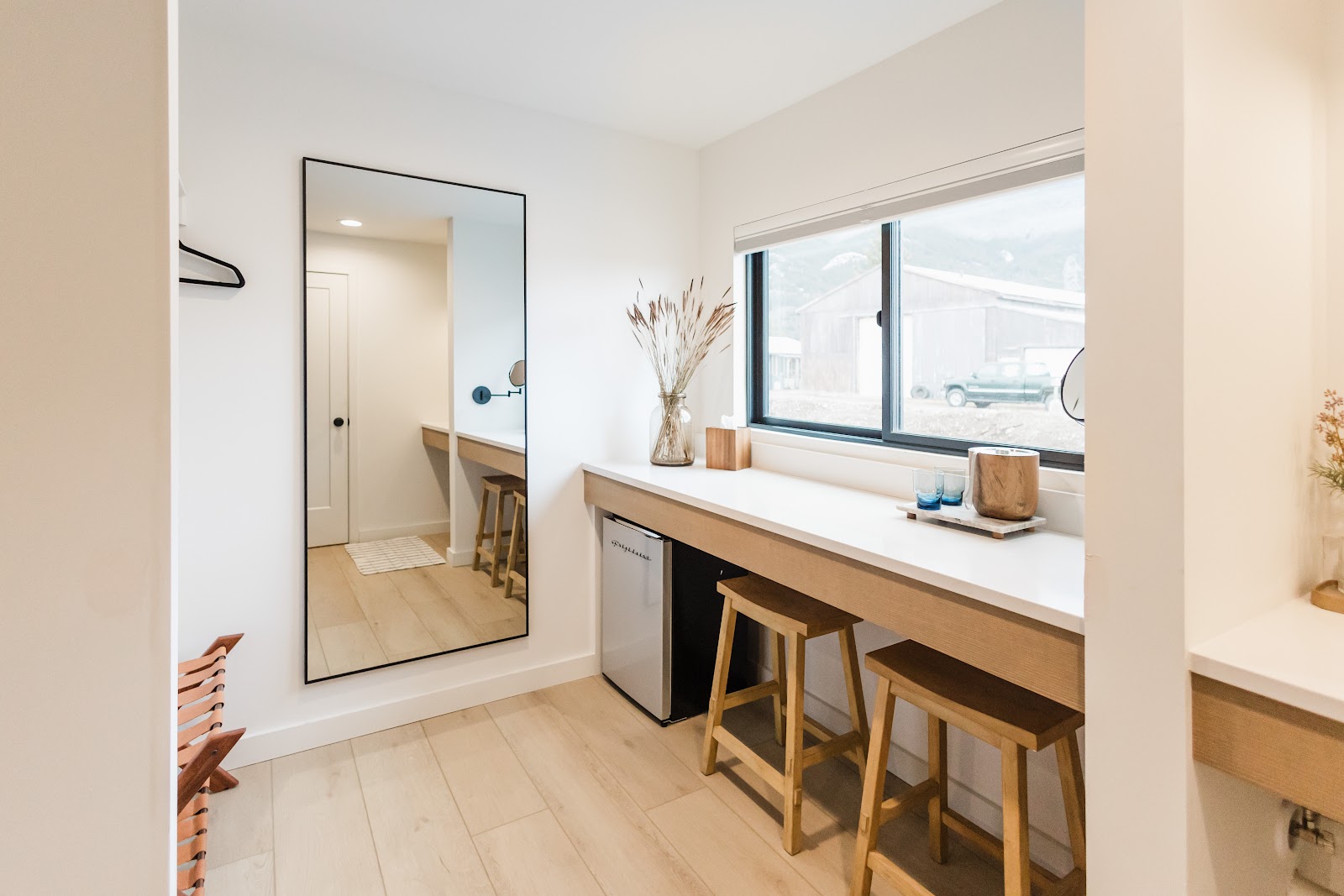 Long vanity counter with a large mirror and two wooden stools in Glacier National Park lodging interior.