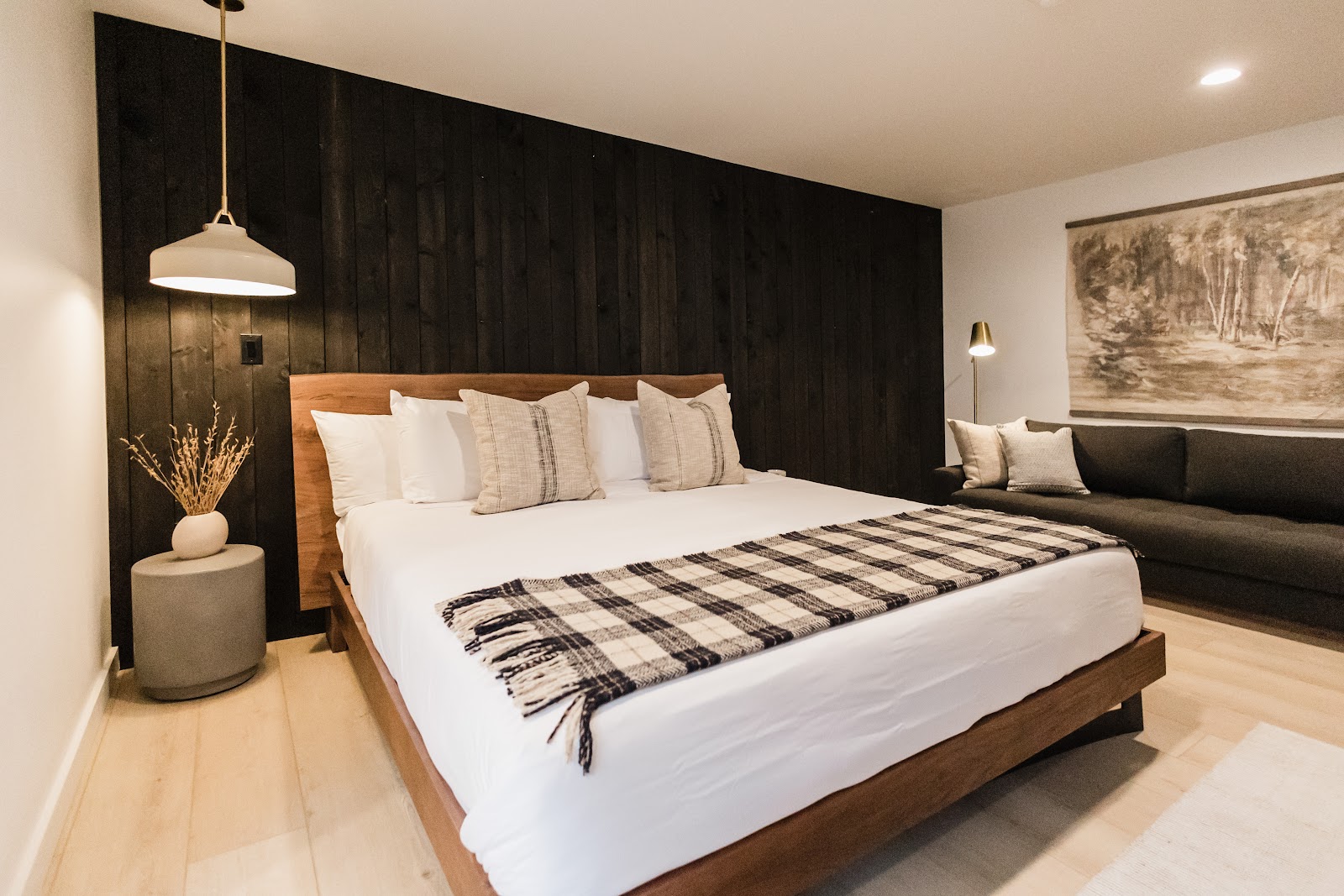 Glacier National Park lodge bedroom with a dark wood accent wall, white linens, and neutral plaid throw.