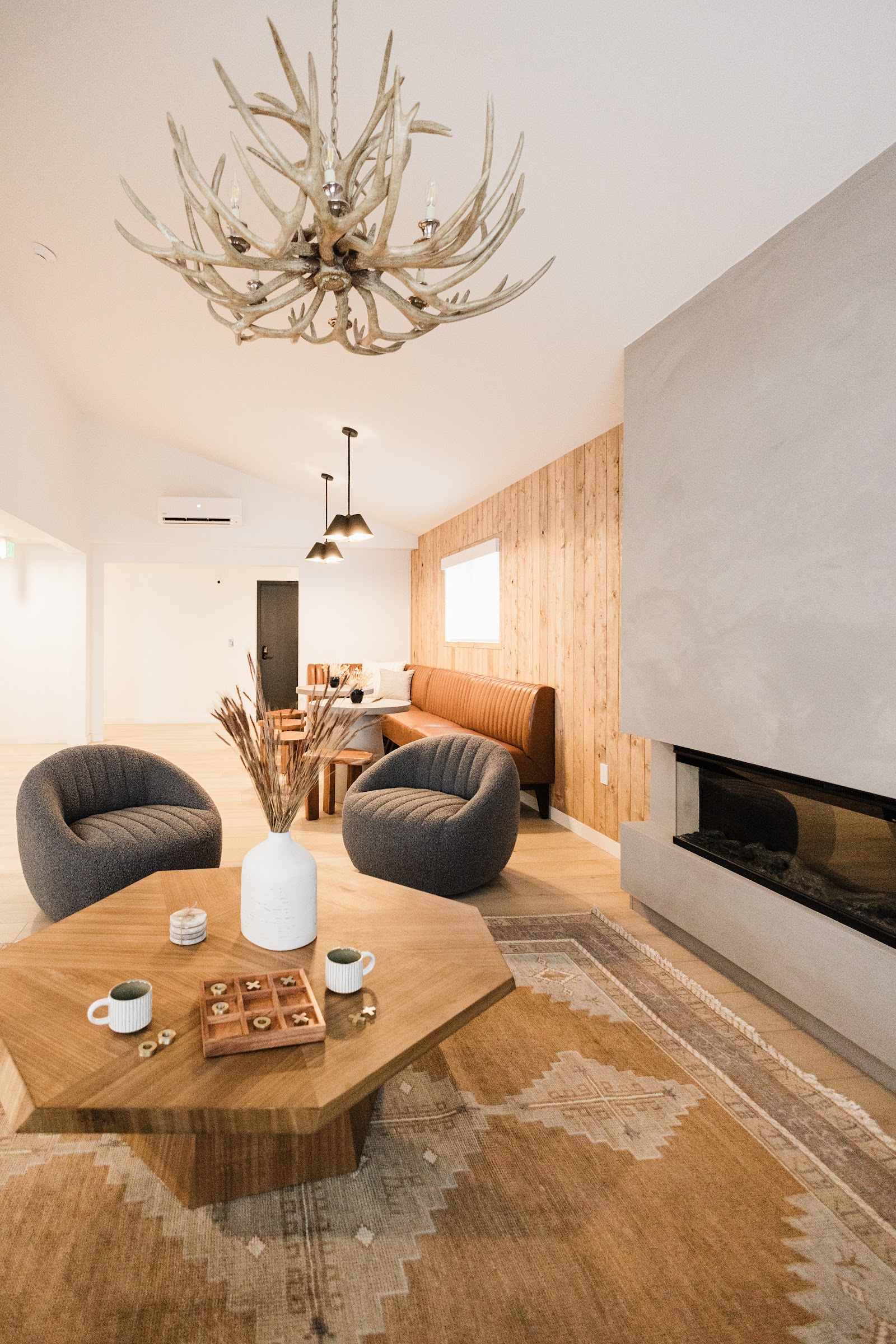Lodge living room in Glacier National Park features a rustic antler chandelier and a modern fireplace.