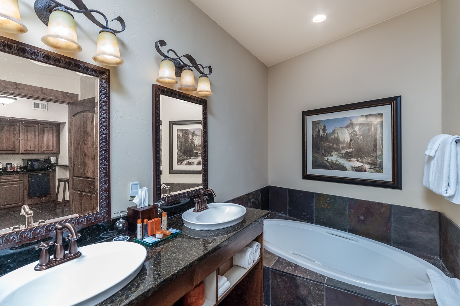 Lodge-style bathroom with dual sinks, a freestanding tub, and framed art in Glacier National Park.