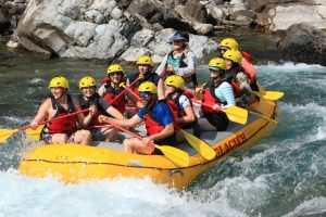 A group of paddlers wearing yellow helmets navigates the Flathead River rapids in Glacier National Park.