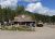 Whitewater rafting facility at Glacier National Park with a wooden building, buses, and people outside on a sunny day.