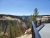 Inspiration Point overlook in Yellowstone National Park with a metal railing, canyon walls, pines, and a river below.