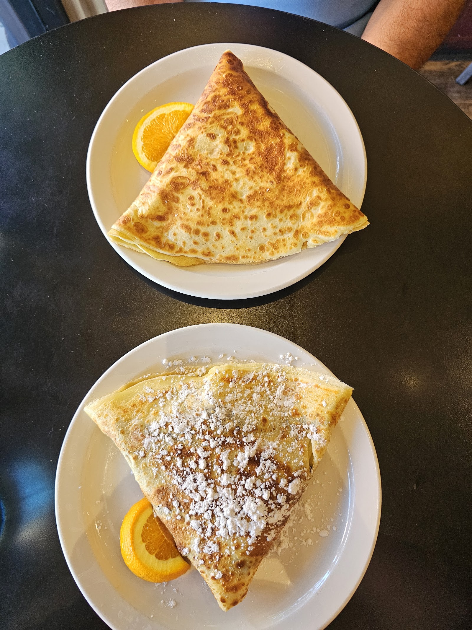 Two folded crepes with orange slices on a white plate, served in Glacier National Park restaurant setting.