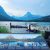 Swiftcurrent Lake at Glacier National Park features towering peaks, a wooden dock, and colorful kayaks on calm water.