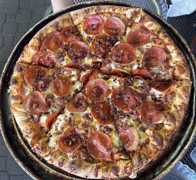 Pepperoni pizza with melted cheese and a browned crust in a round pan, served hot at Yellowstone National Park.