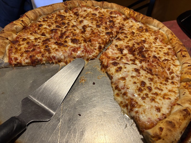 Cheese pizza on a metal tray with a pizza cutter nearby, casual restaurant scene in Yellowstone National Park.