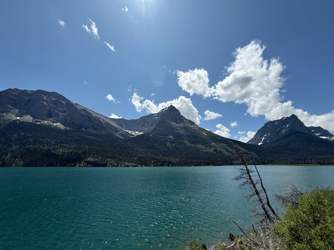 Saint Mary Falls Trail along turquoise Saint Mary Lake in Glacier National Park under a bright summer sky.