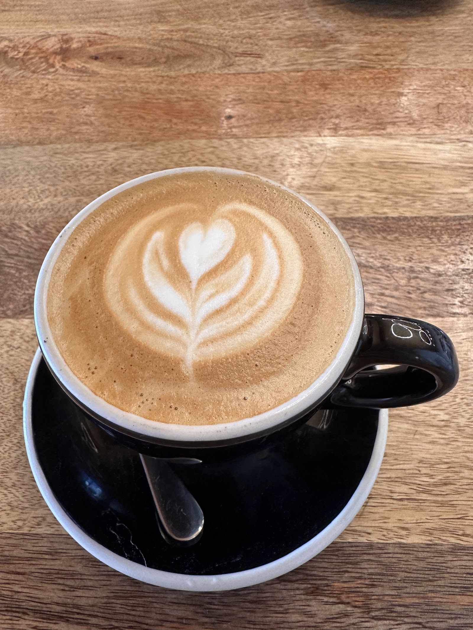 Creamy latte with heart-shaped latte art served in a Glacier National Park cafe, captured indoors.