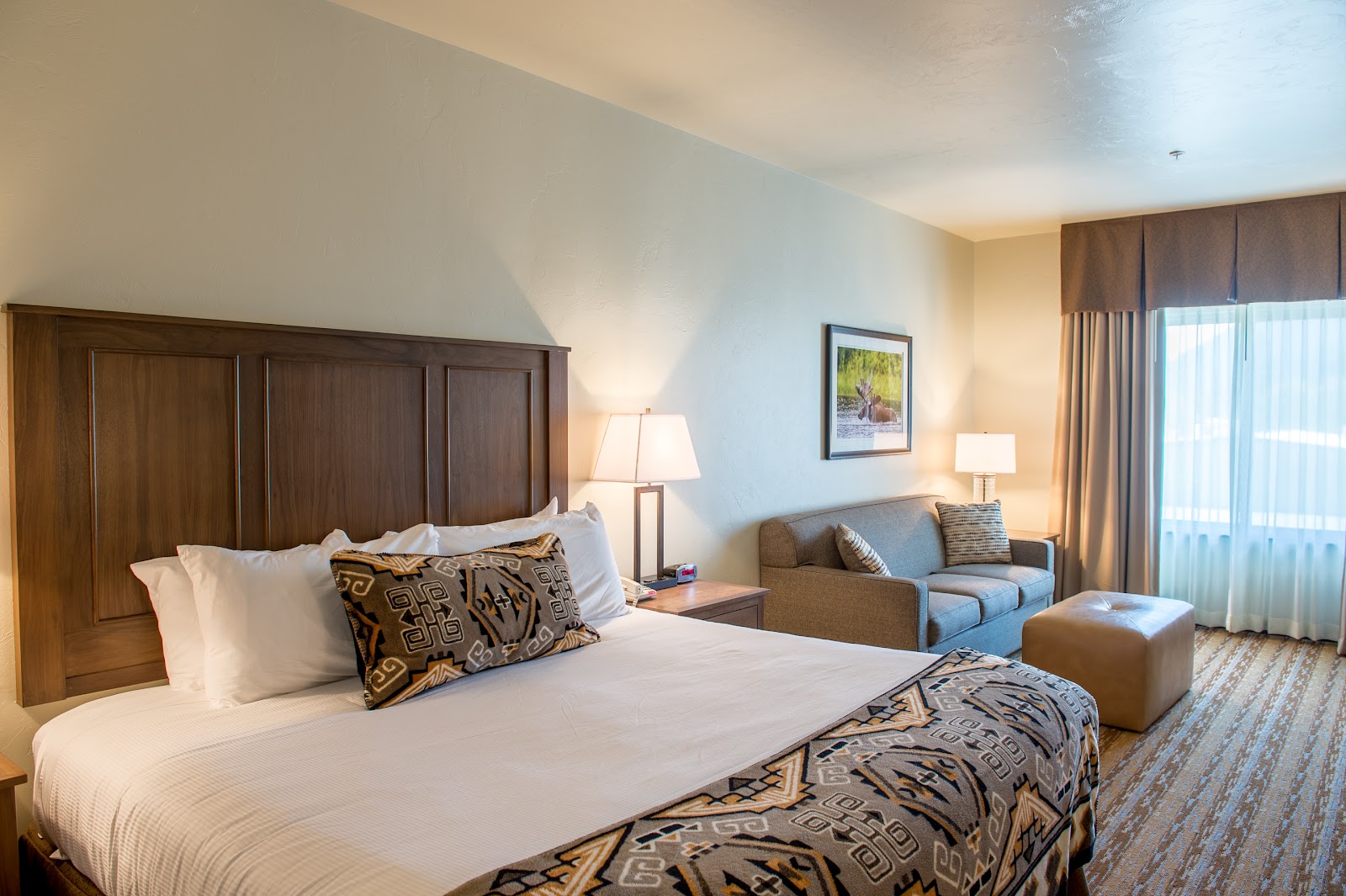 Glacier National Park lodge guest room with a large wooden headboard, white bedding, and patterned decorative pillows.