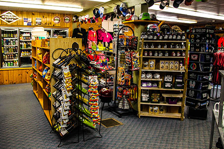 Glacier Highland lodge lobby gift shop interior at Glacier National Park, filled with racks of apparel, souvenirs, and snacks.