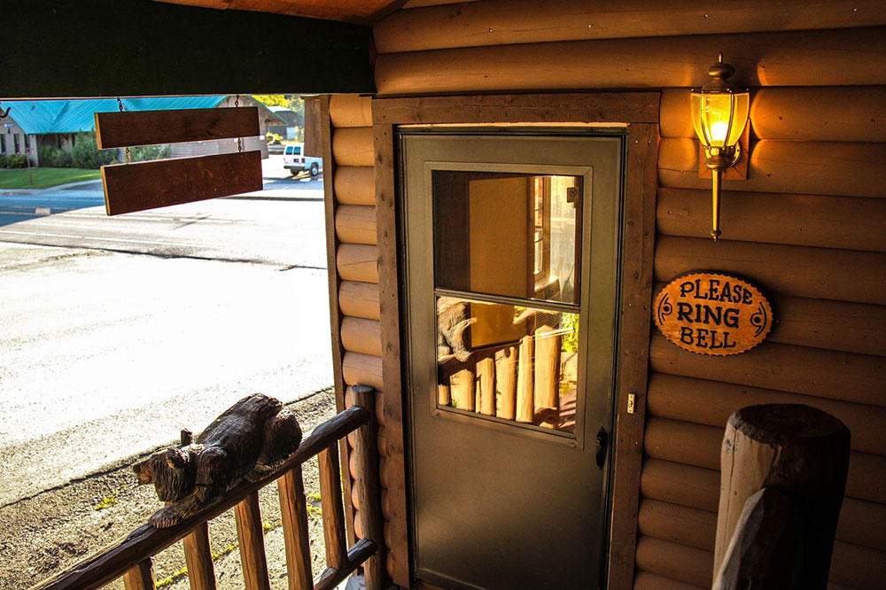 Lodge porch with a wooden railing and door at Glacier National Park, a simple rustic lodging exterior.