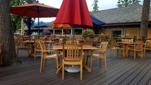 Outdoor dining deck with orange umbrellas at a lakeside restaurant in Glacier National Park.