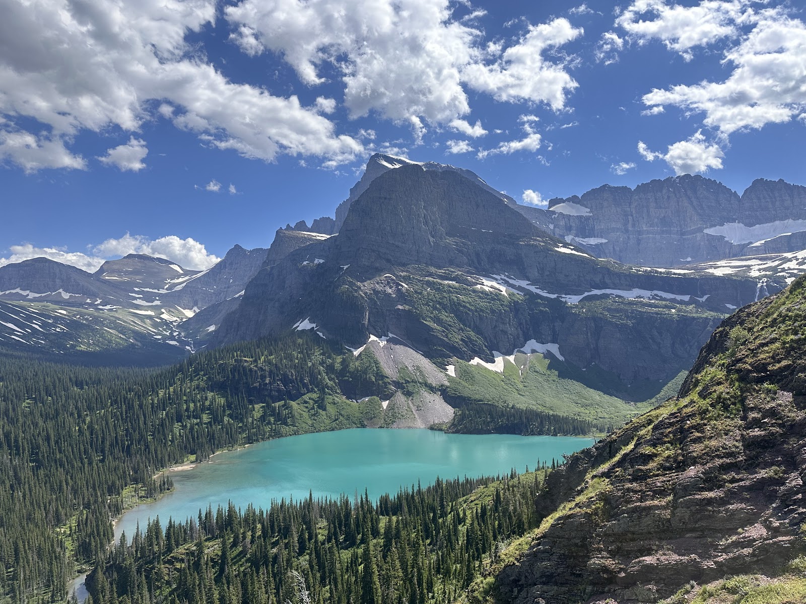 Grinnell Glacier Overlook at Glacier National Park reveals a turquoise lake set against jagged, snow-dusted peaks.
