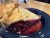 Berry pie slice with a flaky golden crust and a bubbling berry filling on a deep blue plate in Glacier National Park dining setting