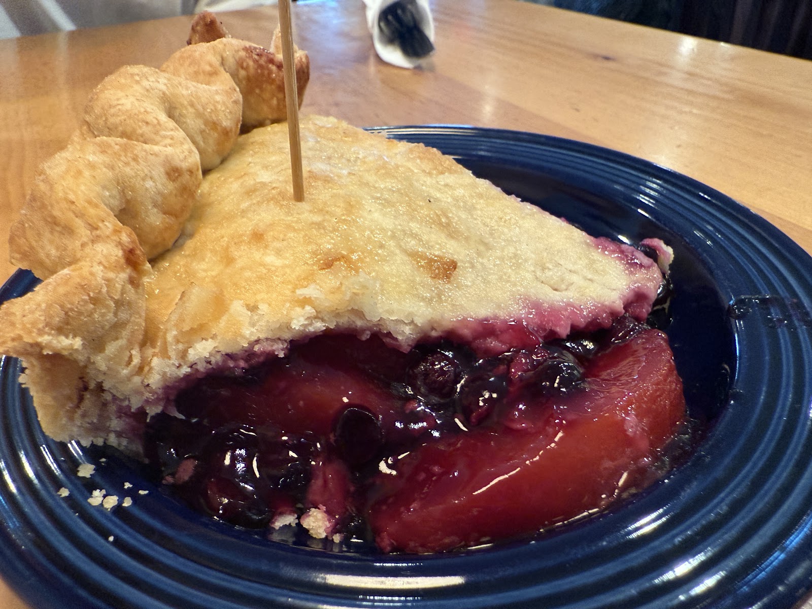 Berry pie slice with a flaky golden crust and a bubbling berry filling on a deep blue plate in Glacier National Park dining setting