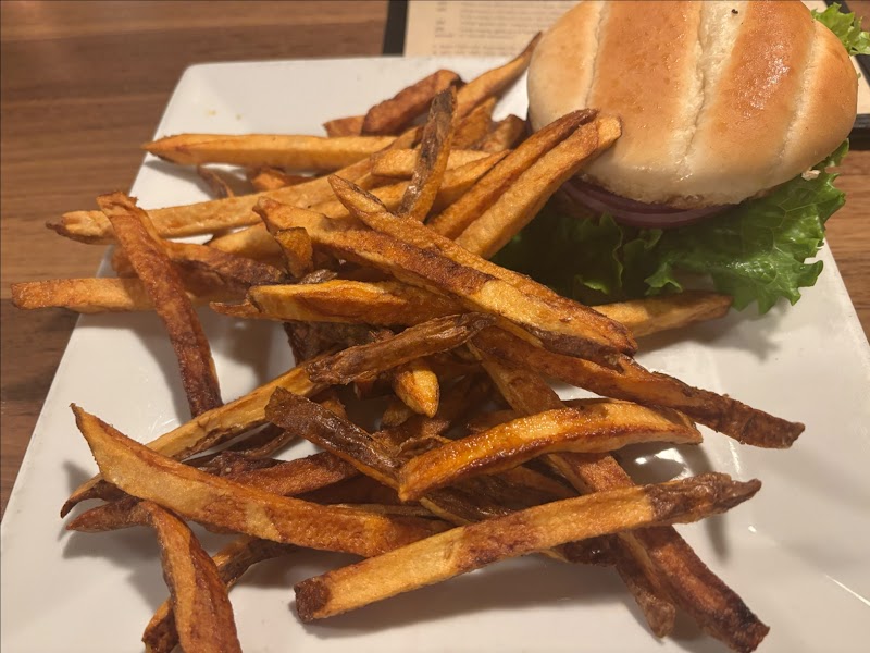 Fries piled next to a cheeseburger with lettuce on a white plate at a restaurant in Yellowstone National Park.