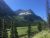 Florence Falls in Glacier National Park framed by alpine peaks, dense evergreen forest, and a meandering river.