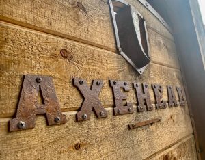Axehead sign letters mounted on a rustic wooden wall at a Glacier National Park gift shop storefront.