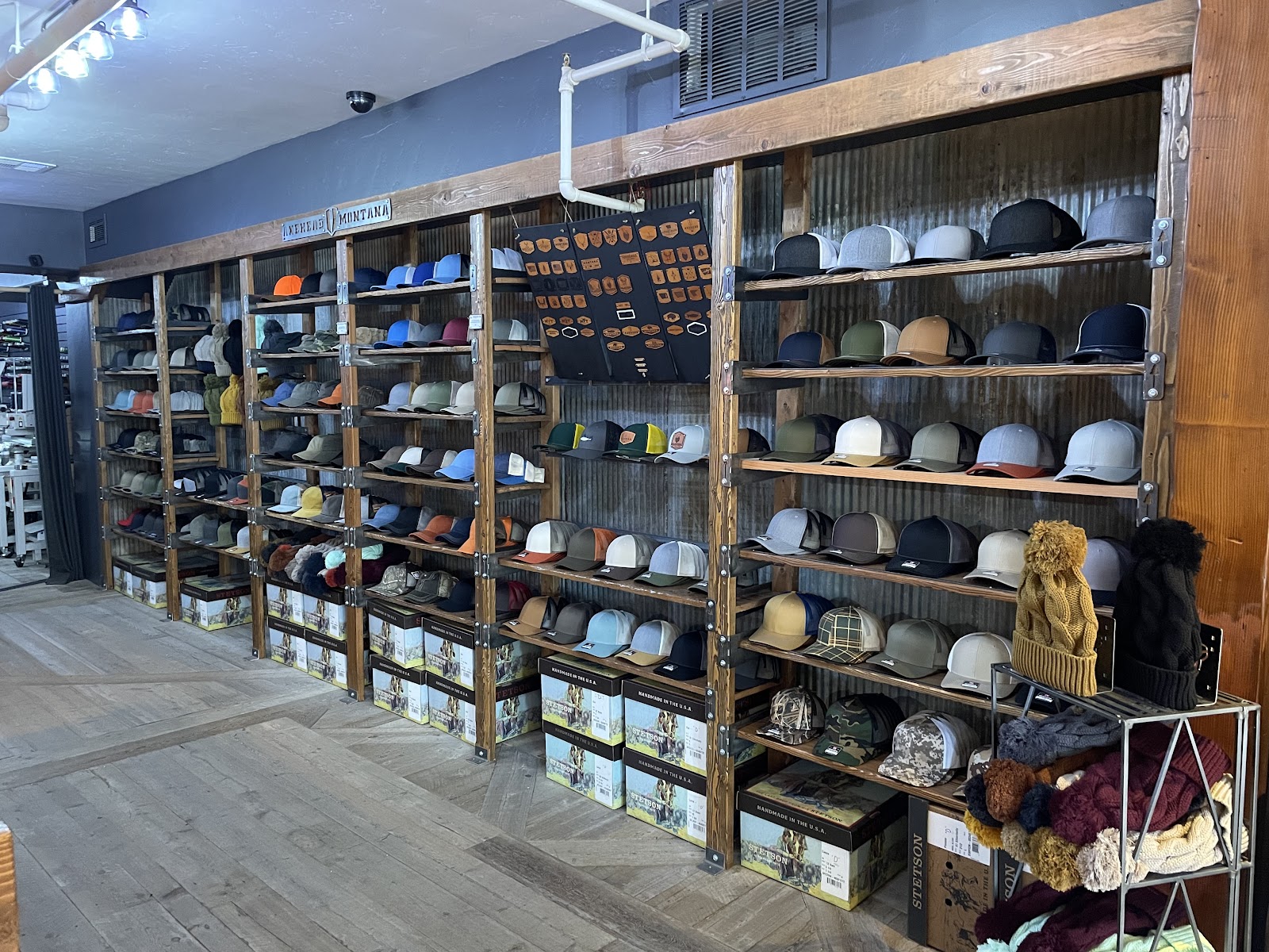 Inside a Glacier National Park gift shop, rows of hats line wooden shelves along corrugated metal walls.