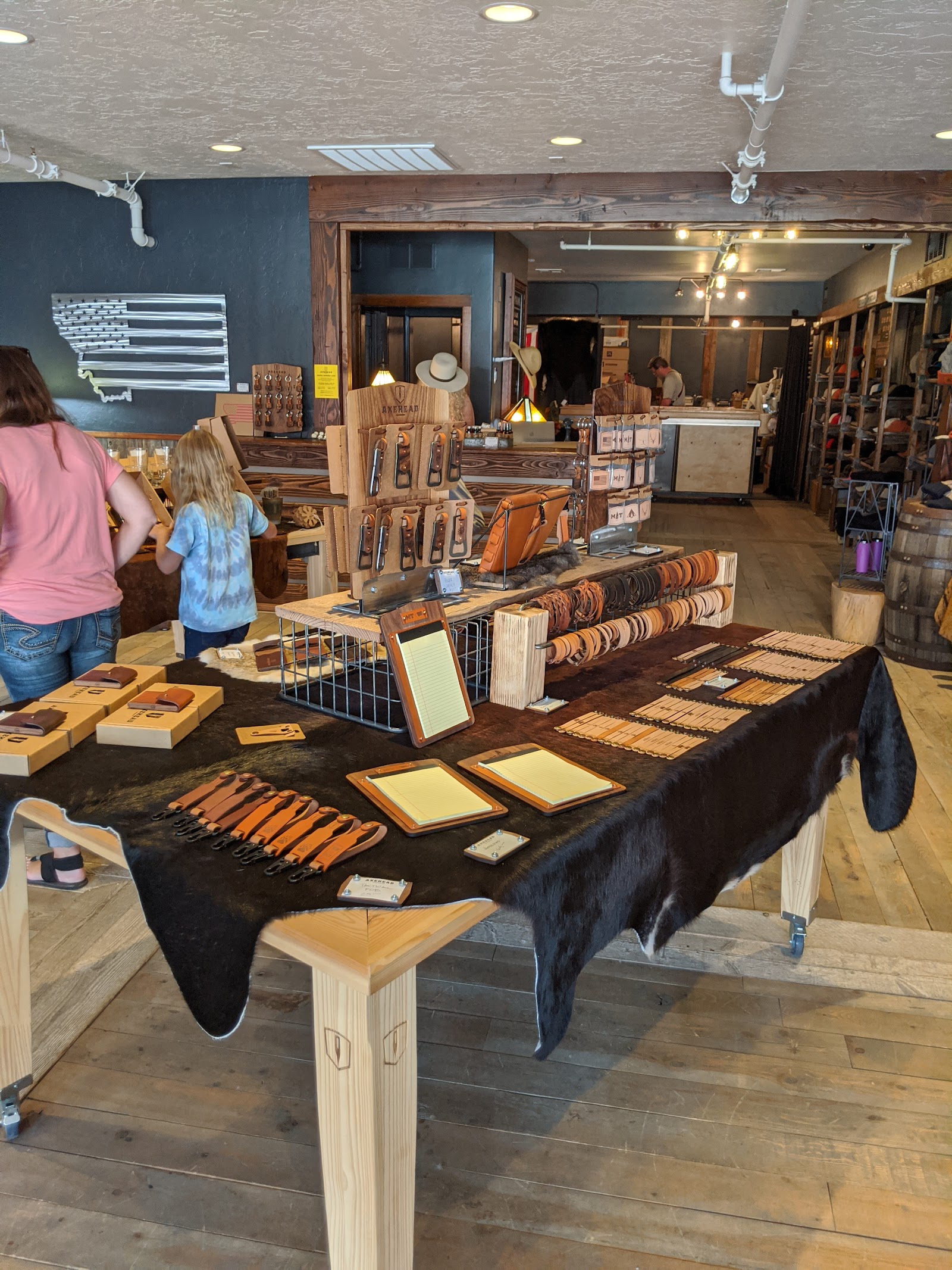 Leather goods and axe-themed items are displayed for sale inside a Glacier National Park gift shop.