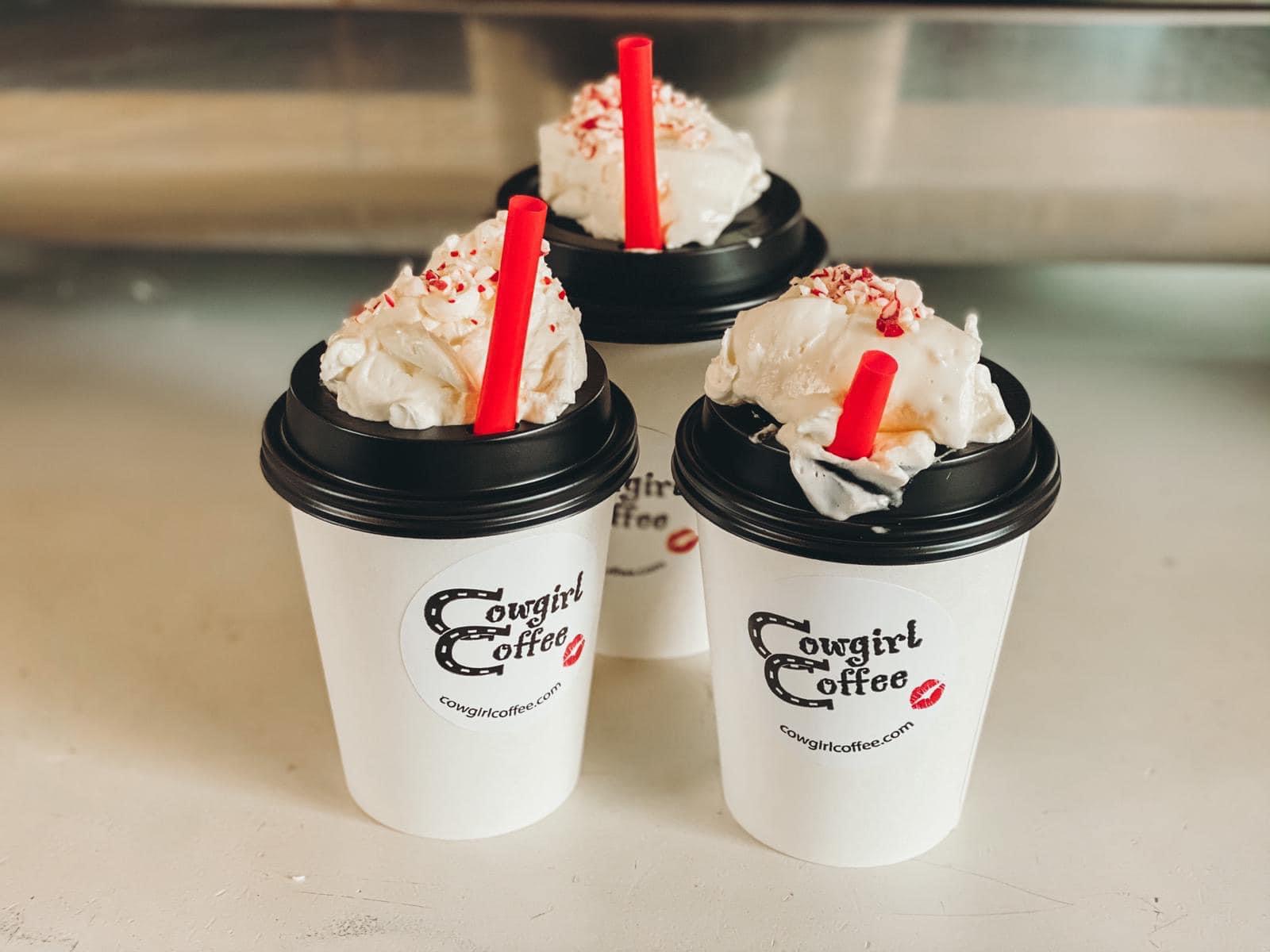 Three coffee cups with whipped cream and red straws sit on a counter inside a Glacier National Park cafe.