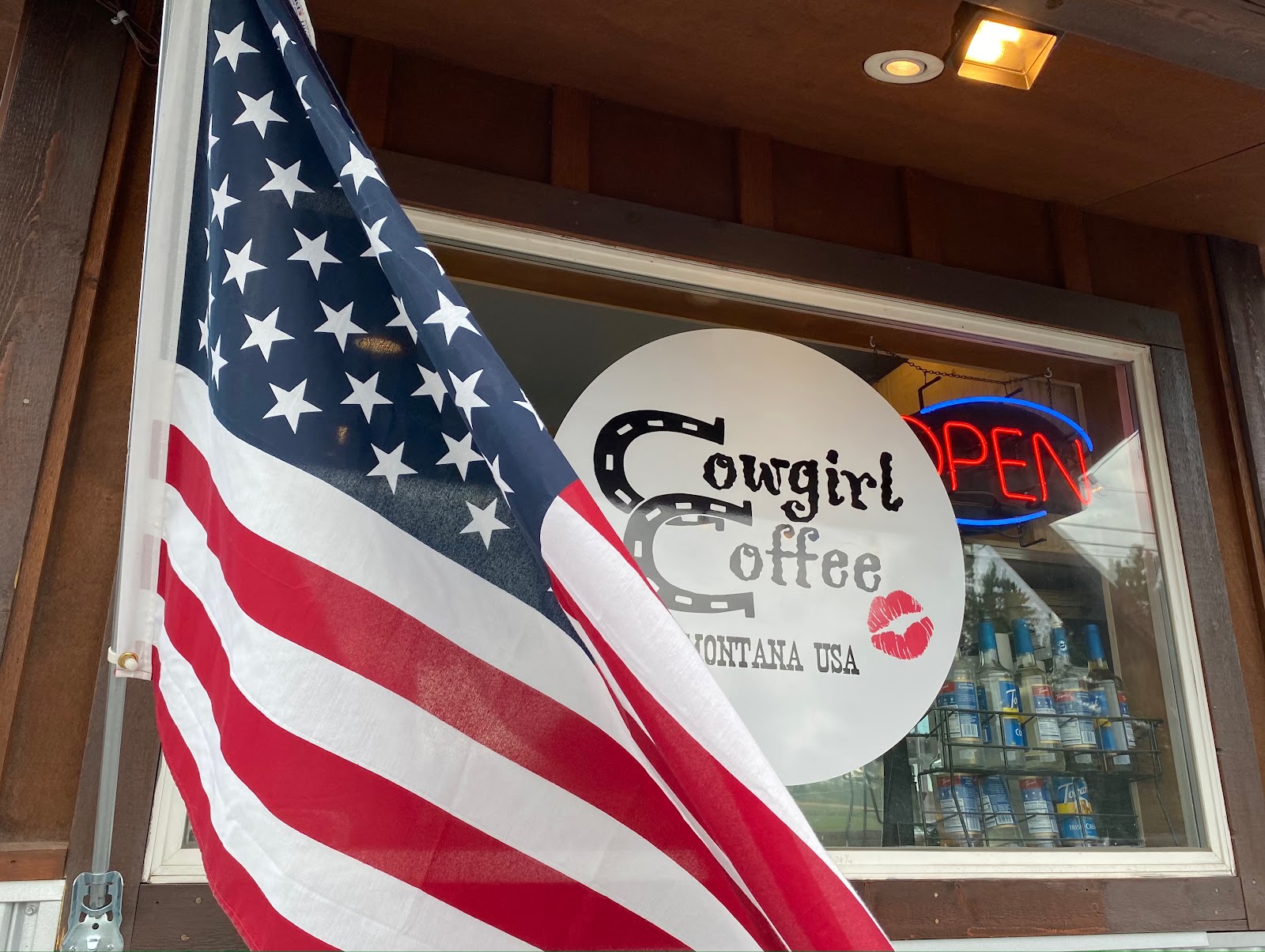Flag waves in front of a Glacier National Park shop window near Polebridge, Montana, advertising coffee.