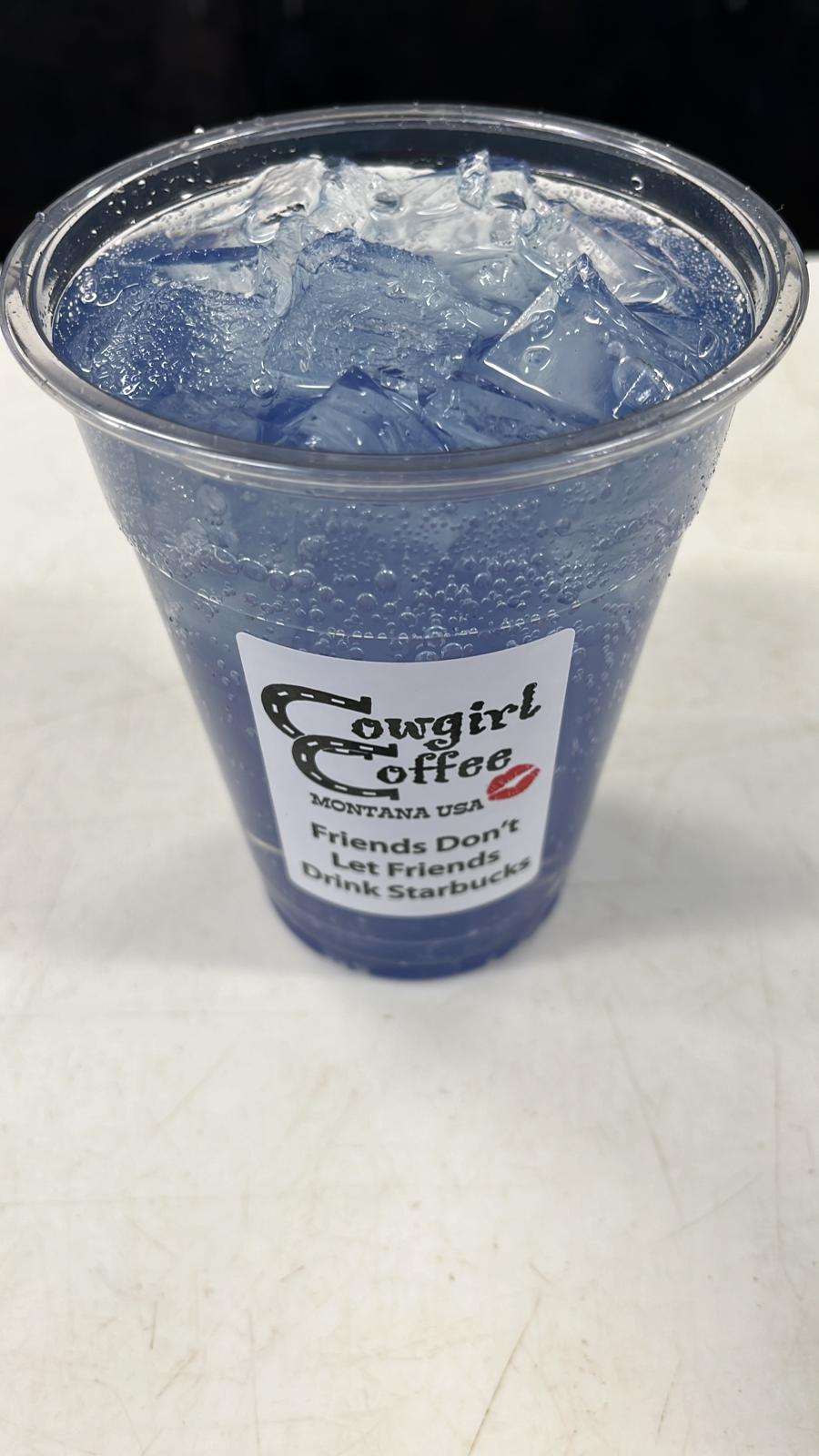 Blue iced beverage in a clear plastic cup at a Glacier National Park cafe, with a bold label on the cup.
