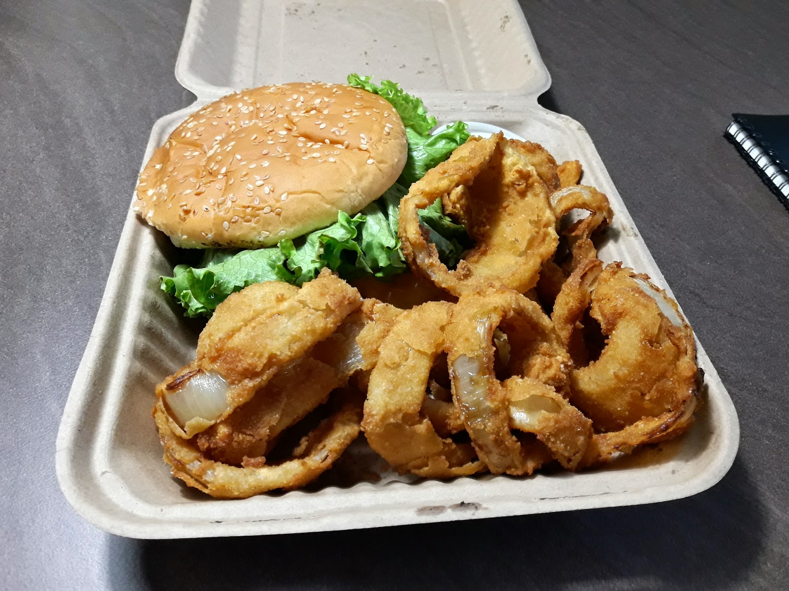 Hamburger with sesame bun and fresh lettuce served with crispy onion rings at a Glacier National Park eatery.
