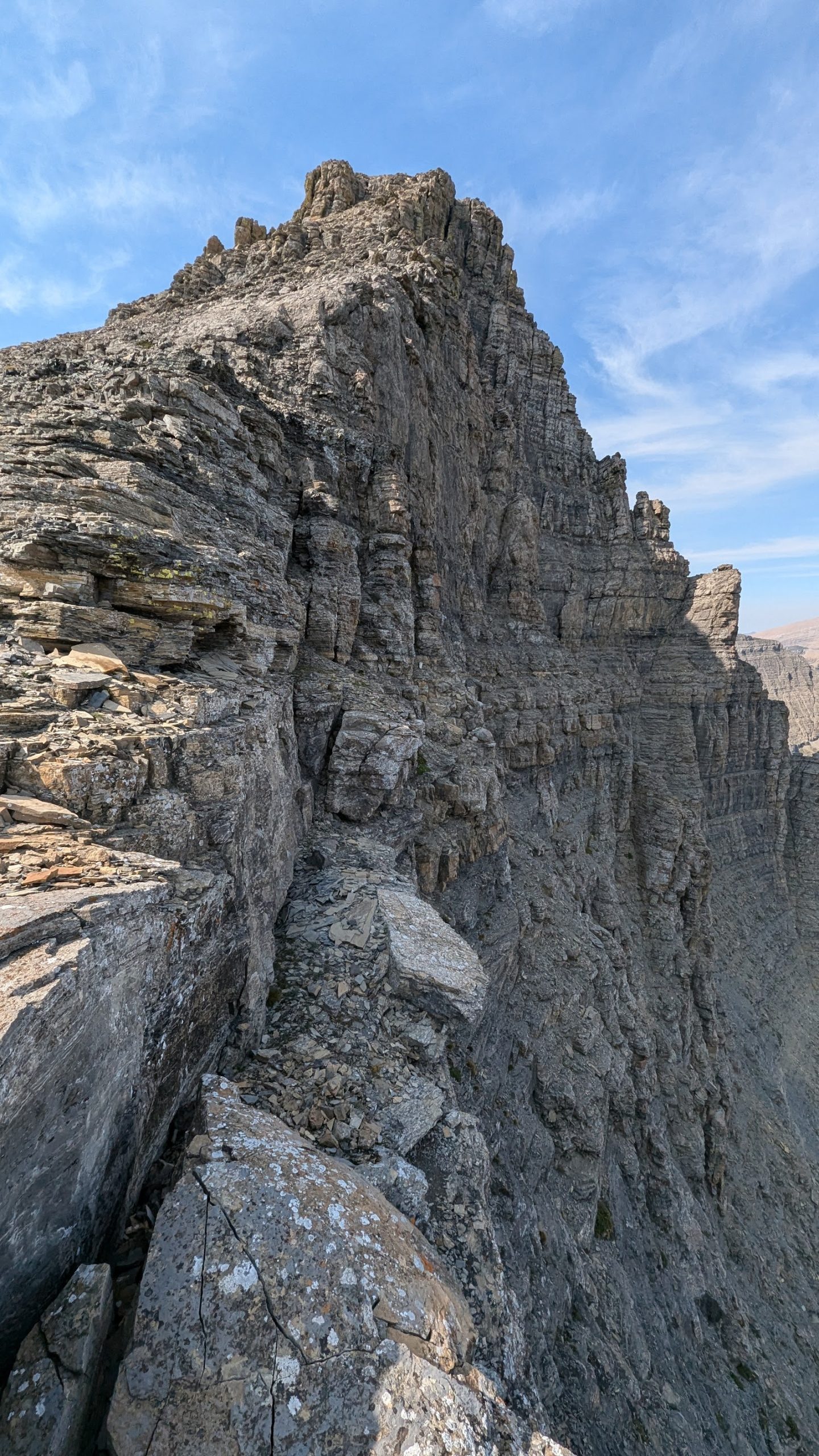 Flinsch Peak rises beside rugged granite cliffs in Glacier National Park under a bright blue sky.