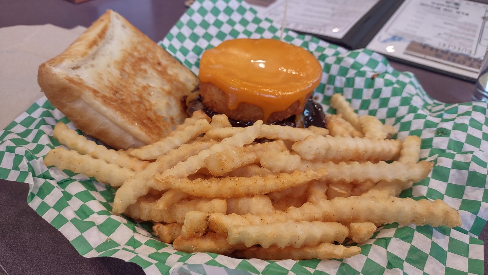 Cheeseburger with melted cheddar and a side of crinkle-cut fries served at a Glacier National Park dining spot.