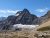 Siyeh Pass Trail winds through rugged Glacier National Park granite peaks under a bright blue sky.