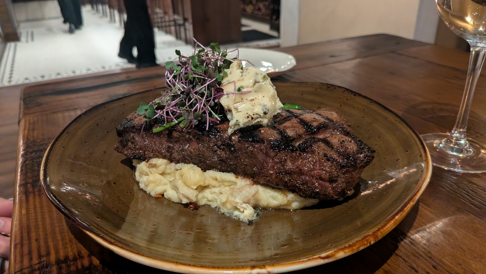 Juicy grilled steak with crosshatch marks rests on creamy mashed potatoes, topped with herb butter and microgreens in Glacier National Park.