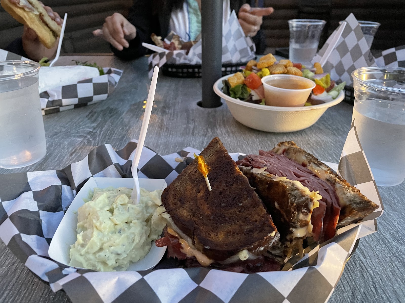 Glacier National Park roast beef sandwich served with potato salad at a casual outdoor eatery in summertime.