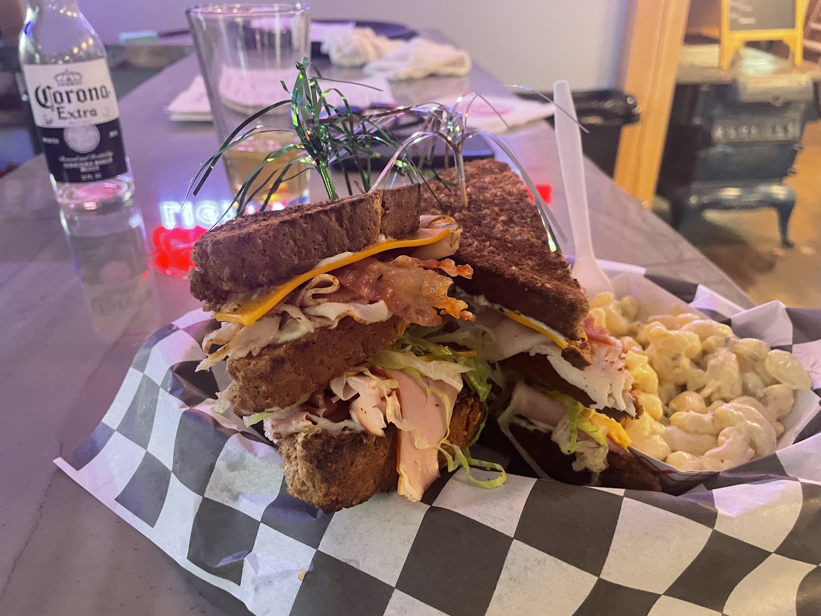 Hearty turkey club sandwich with bacon and cheese from a Glacier National Park dining spot, served with macaroni salad.