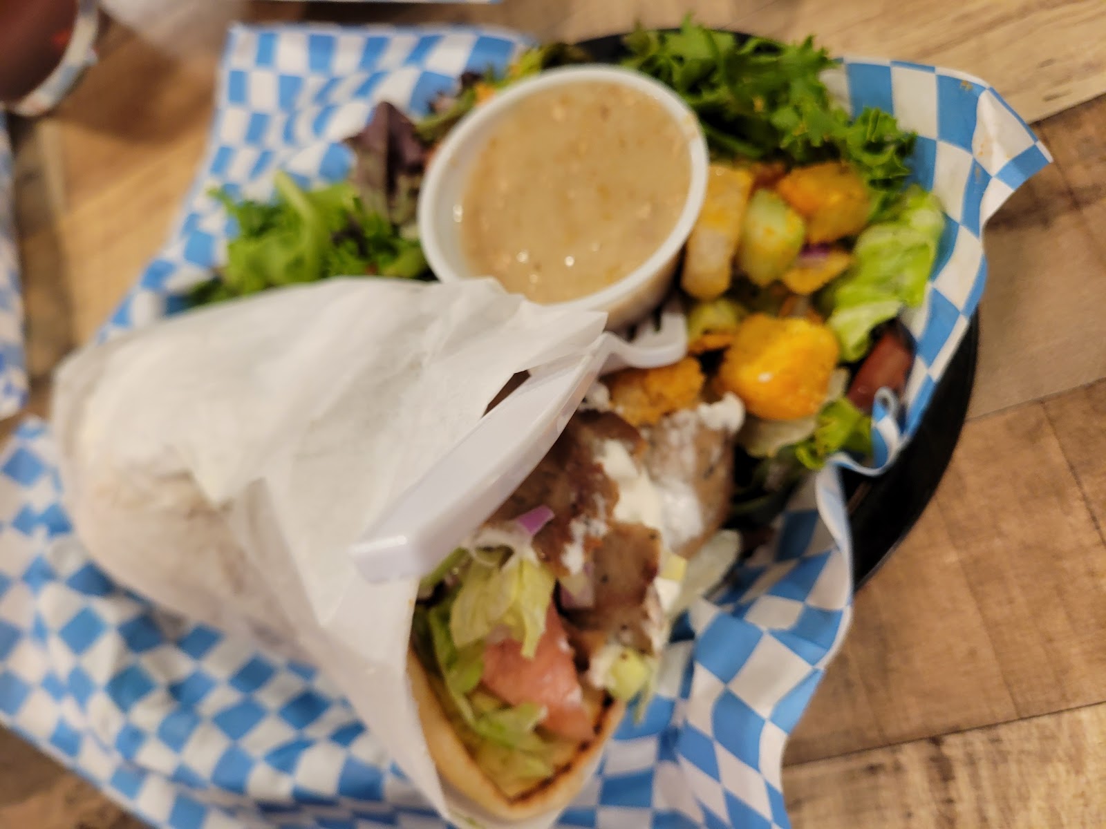 Meal served at a Glacier National Park eatery, arranged in a blue-checkered basket with greens and sauces.