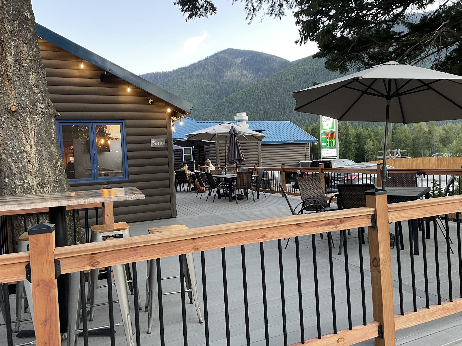 Patio dining deck at a Glacier National Park restaurant with mountain backdrop and warm string lights.