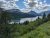 Two Medicine Lake reflects forested slopes and snow-capped peaks under a bright sky in Glacier National Park.